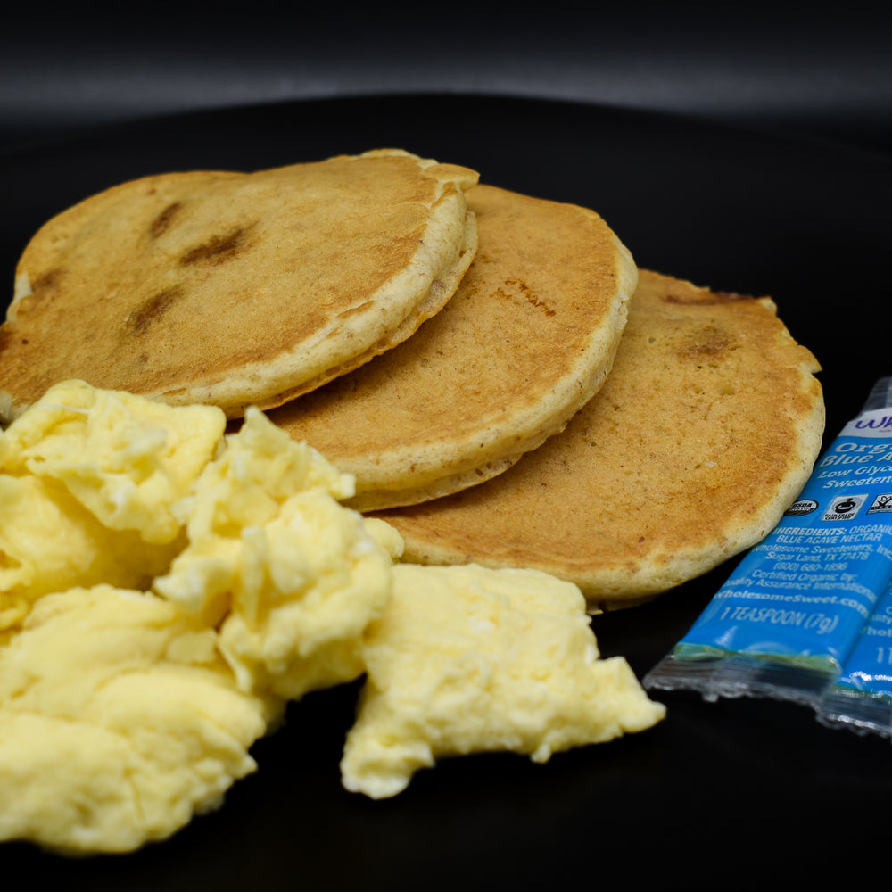 Fluffy granola pancakes with eggs and syrup.