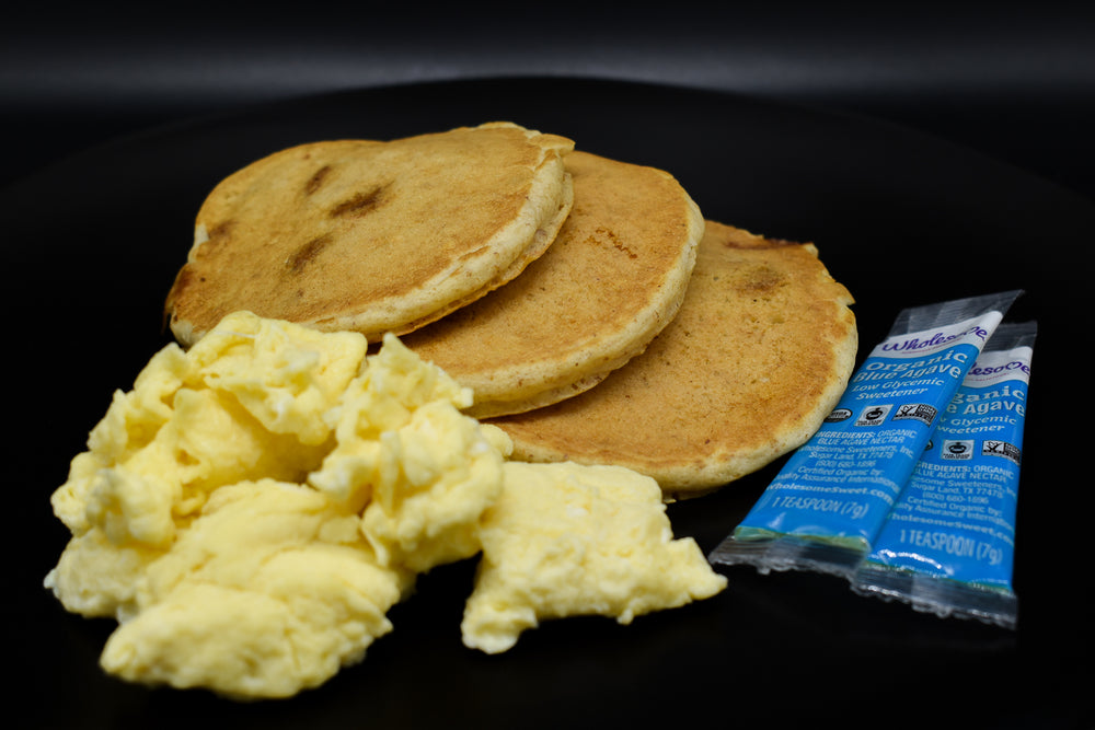 Fluffy granola pancakes with eggs and syrup.